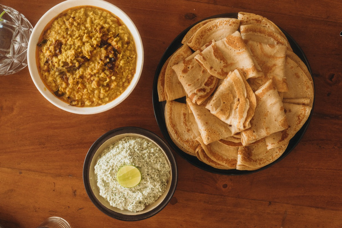 A Sri Lankan spread at Lanka Yoga: a bowl of parippu dhal, a plate of folded pol roti and a bowl of fresh coconut sambol topped with lime